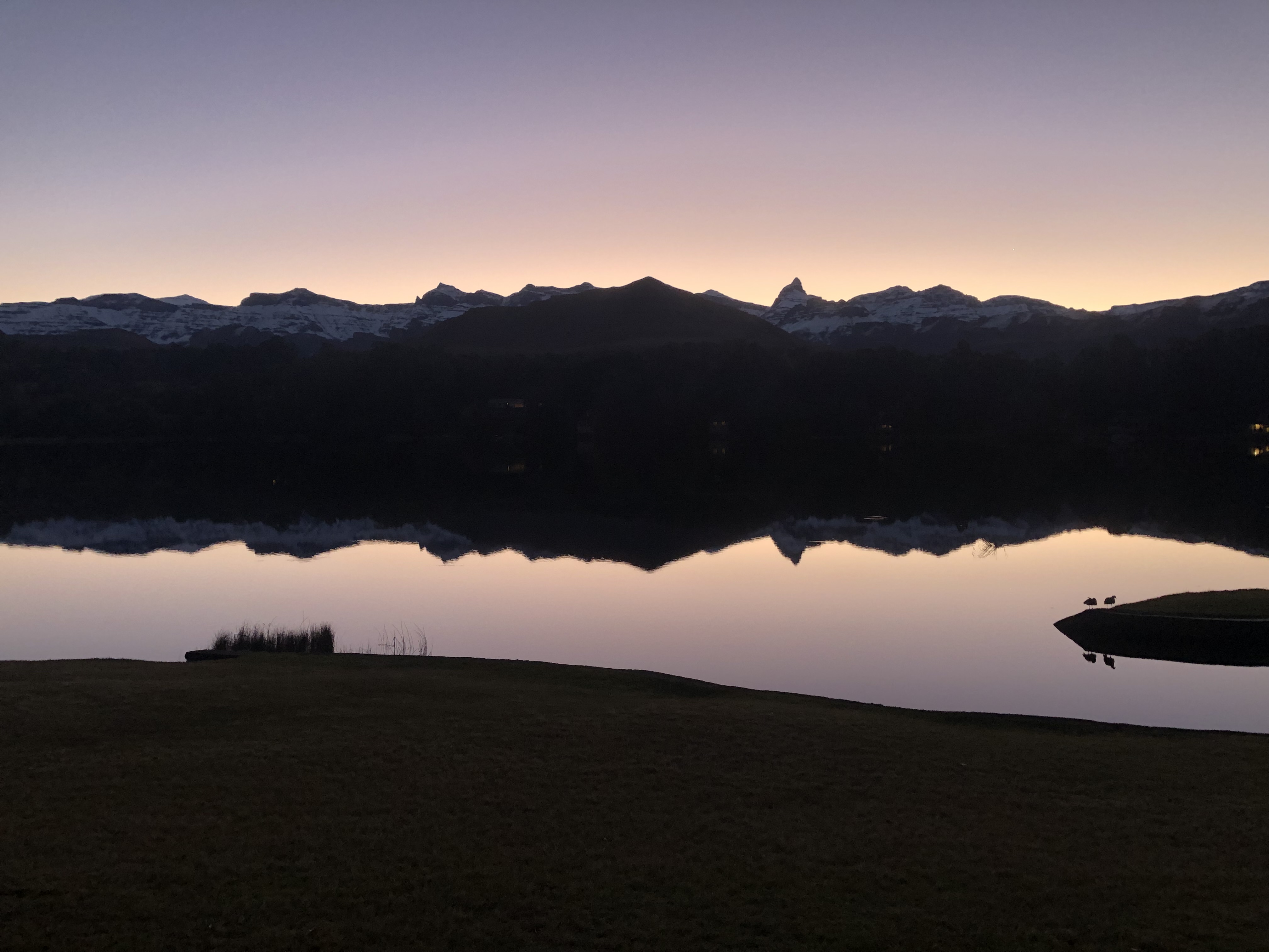 Still alpine lake at dusk reflecting snow-capped mountains